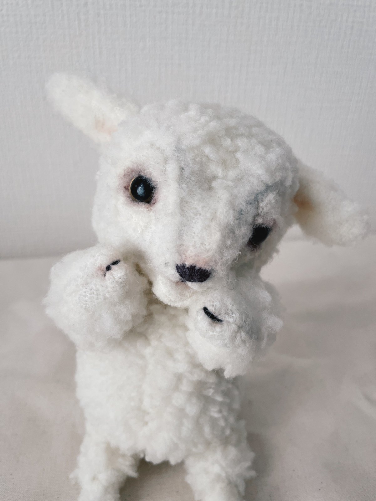 カメラに視線を向けるひつじのぬいぐるみ